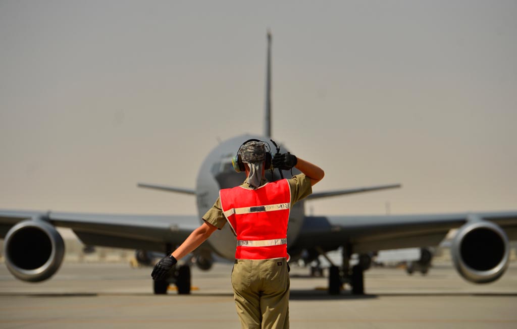 Senior Airman Geoffrey Irwin, 340th Expeditionary Aircraft Maintenance Unit KC-135 Stratotanker crew chief, marshals a Stratotanker, Aug. 5, 2014, Al Udeid Air Base, Qatar. Irwin taxis and marshals about twelve Stratotankers during a 12-hour duty day. Aircraft marshaling is visual signaling between ground personnel and pilots. (U.S. Air Force photo by Staff Sgt. Vernon Young Jr.)